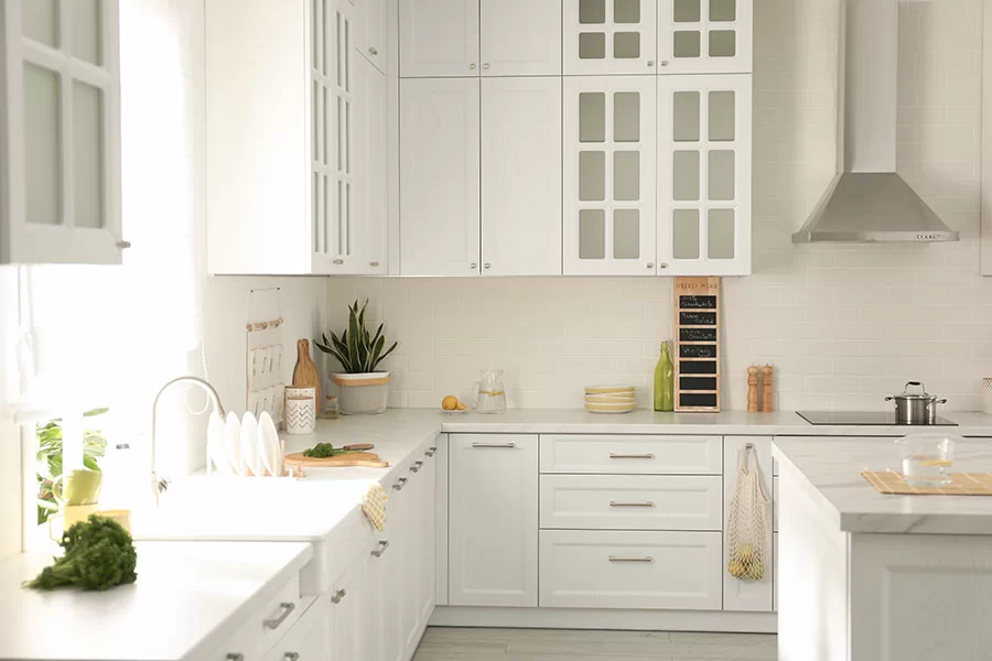 Ett vitt kök med skåp, diskbänk och en kritta-tavla för veckomenyn på bänkskivan – perfekt för en köksrenovering.